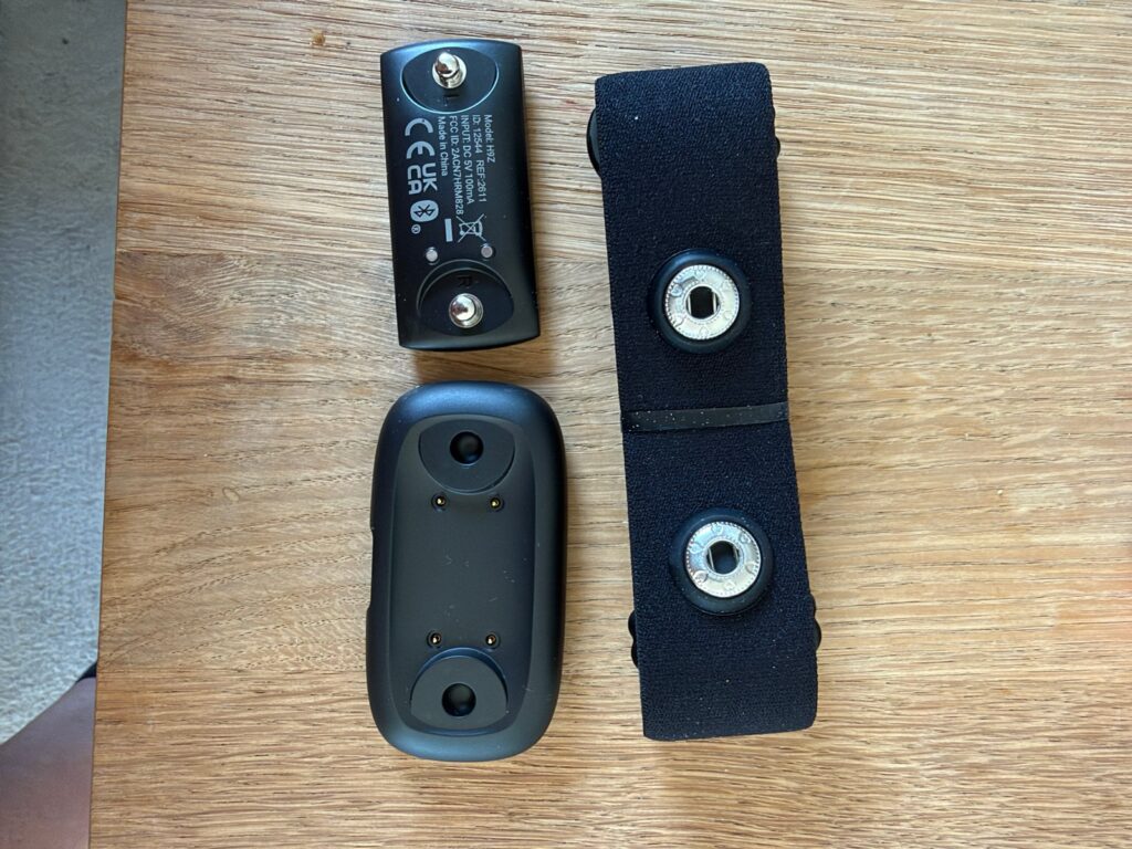 Rückseite des COOSPO-Sensors mit zwei Druckknöpfen, darunter das Ladedock, daneben der Gurt