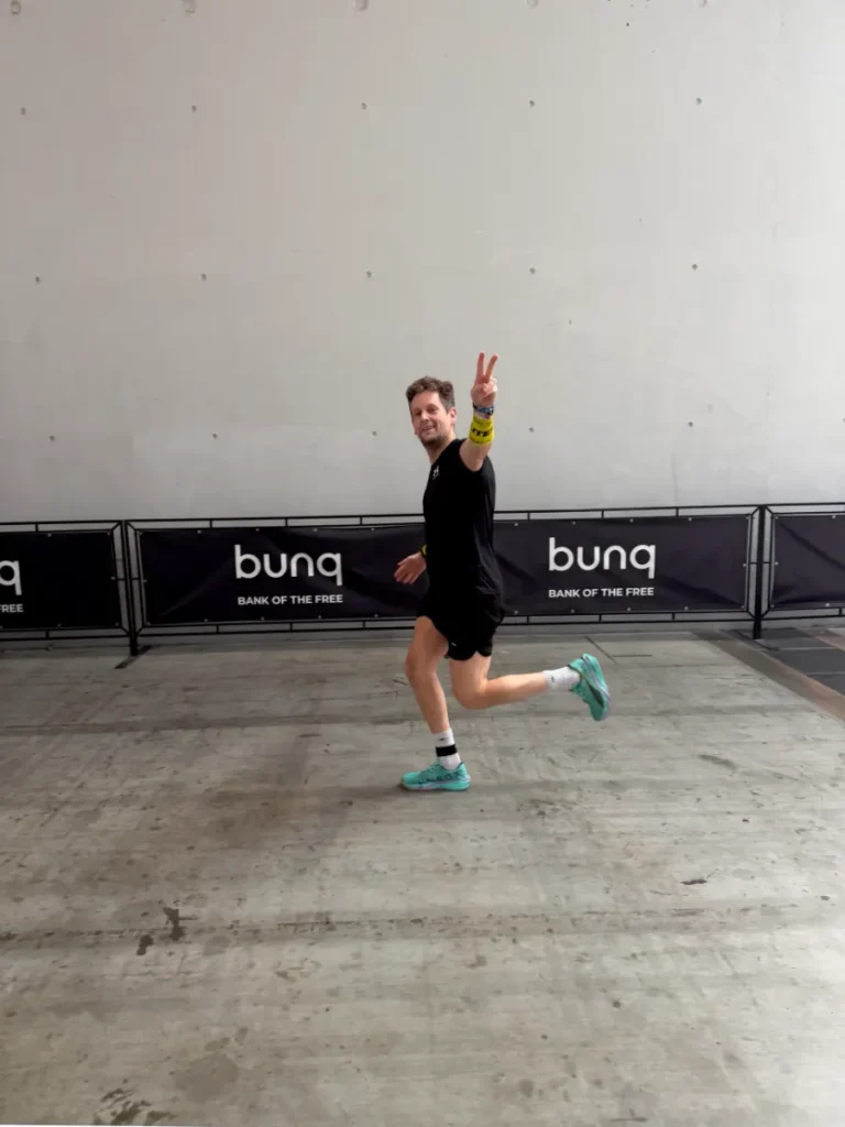 Alex läuft bei HYROX Karlsruhe 2026 über die Laufstrecke und zeigt das Peace-Zeichen
