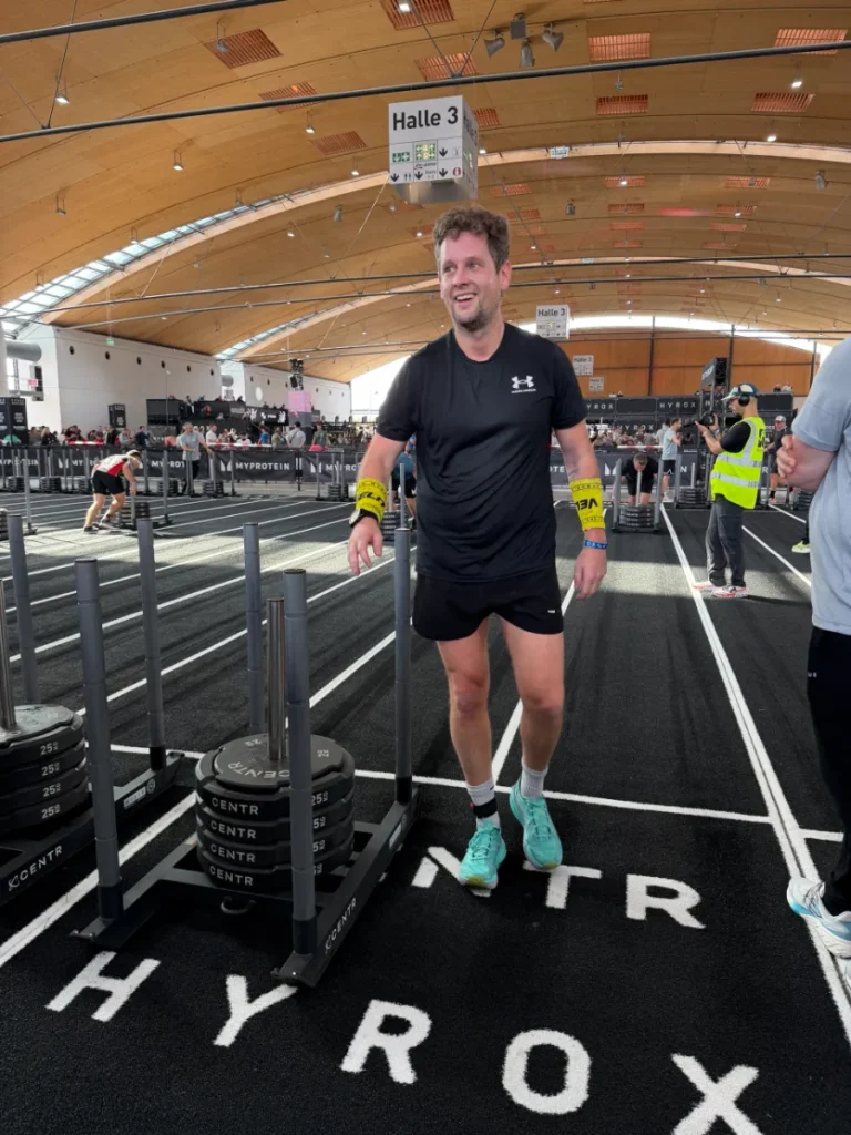 Alex lacht nach dem Sled Push bei HYROX Karlsruhe 2026 in Halle 3