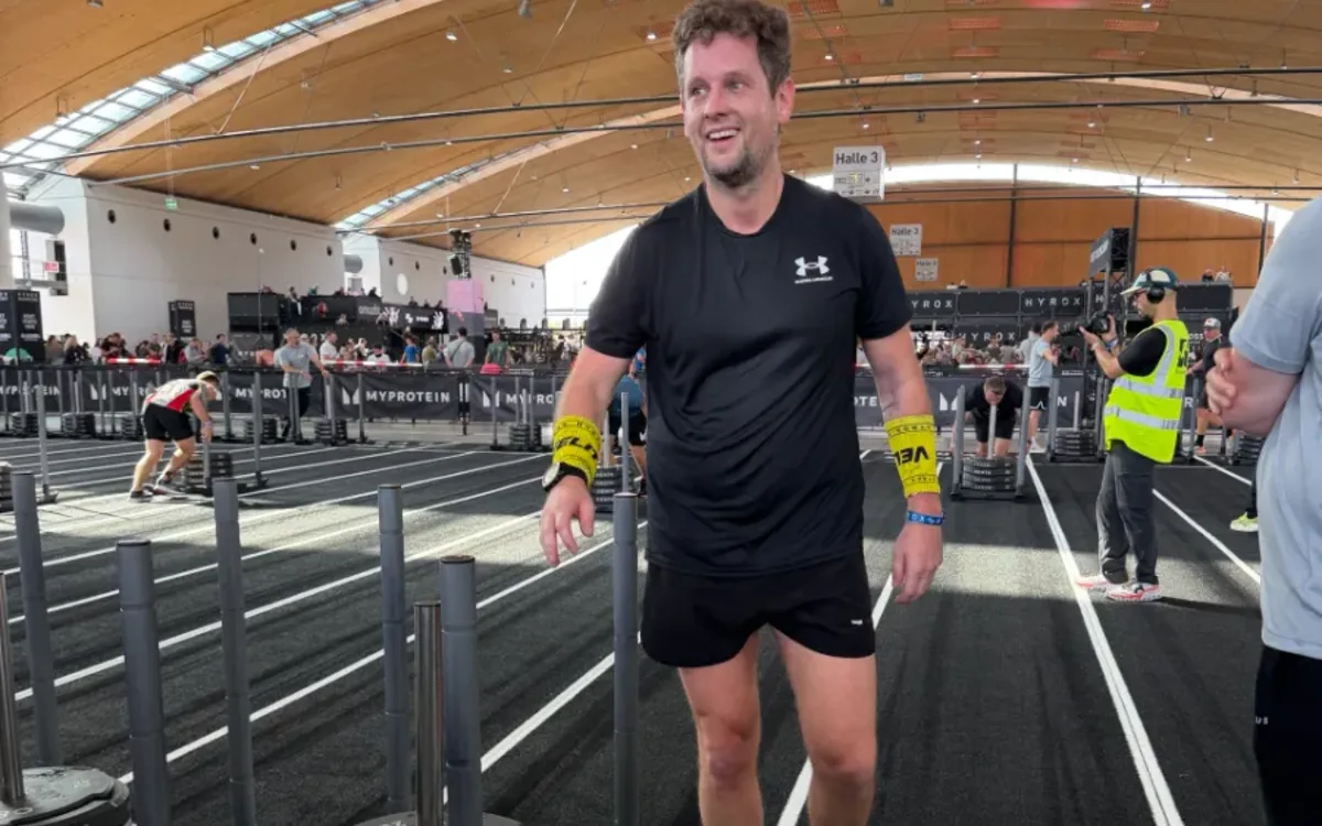 Alex lacht nach dem Sled Push bei HYROX Karlsruhe 2026 in Halle 3