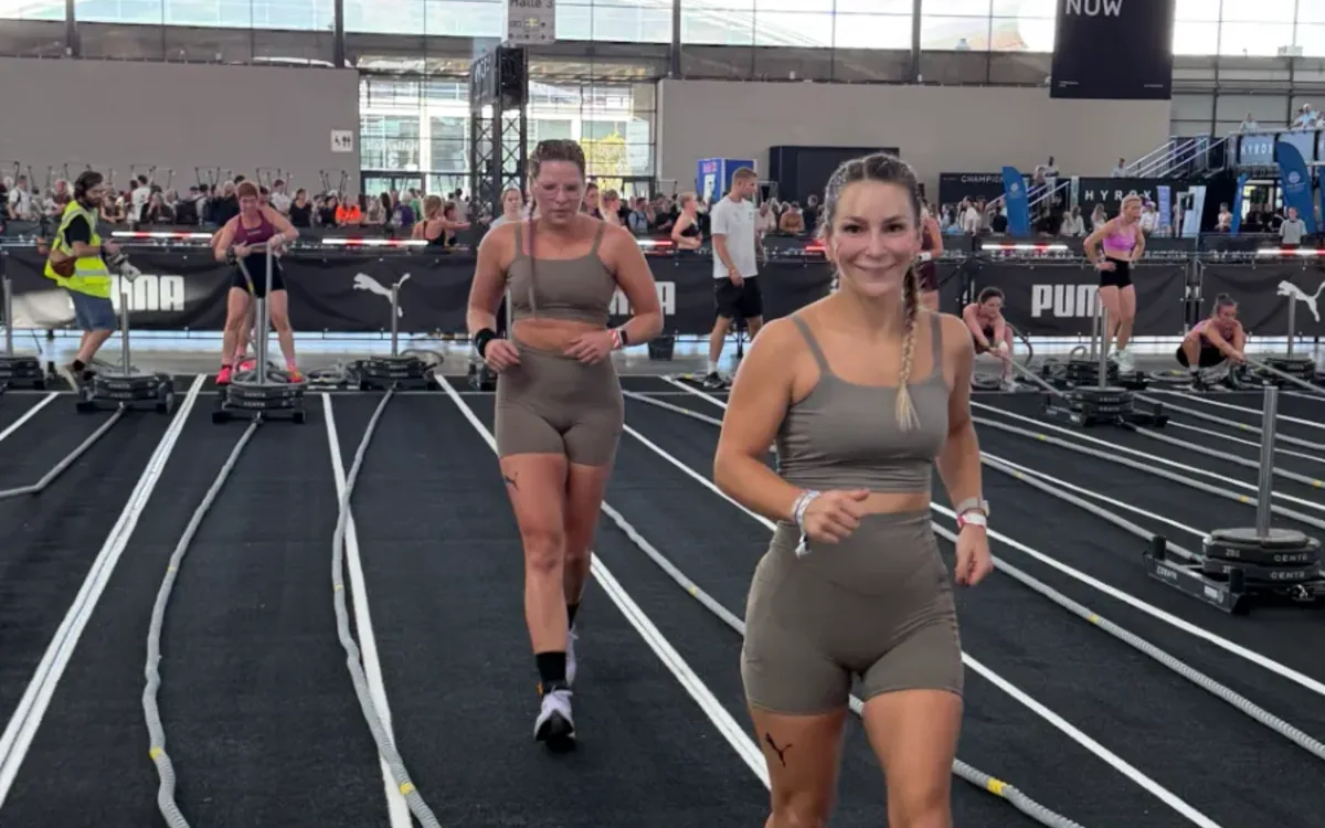 Geri und ihre Doubles-Partnerin laufen bei HYROX Karlsruhe 2026 an den Sled-Pull-Bahnen in Halle 3 vorbei