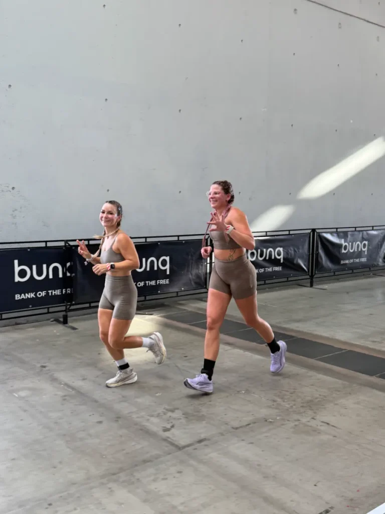 Geri und ihre Doubles-Partnerin laufen bei HYROX Karlsruhe 2026 lachend nebeneinander über die Laufstrecke