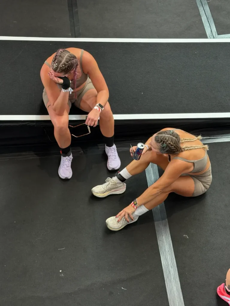 Geri und ihre Doubles-Partnerin sitzen nach dem Ziel bei HYROX Karlsruhe 2026 erschöpft am Boden, von oben fotografiert